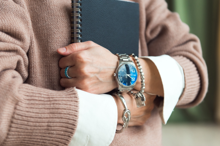 fashion details - watches and bracelets on the hand of a business woman holding planner